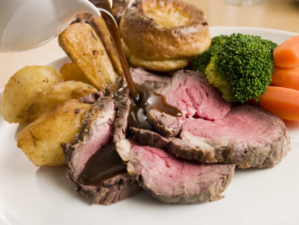 Gravy being Poured on a plate of Roast Beef and Yorkshire Puddin