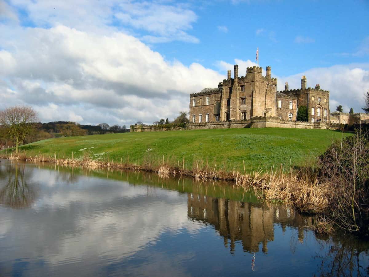 Ripley Castle reflected in a pond and green landscaping